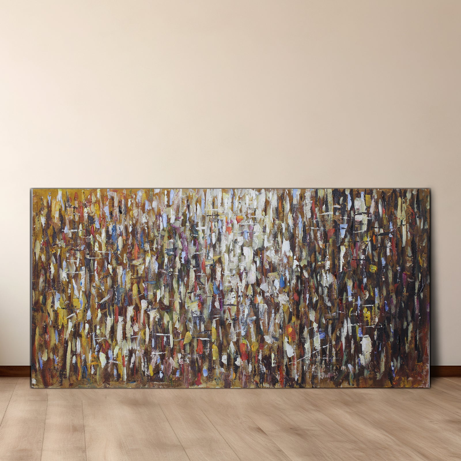 An abstract multicolored oil painting on canvas, featuring a variety of shapes and colors, displayed on a wall in a room with wooden flooring.